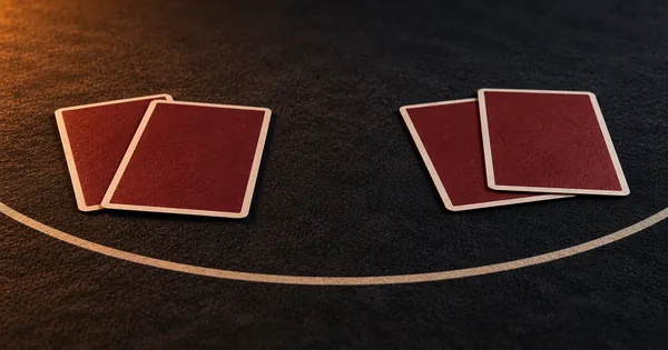 Two pairs of face-down cards on either side of a strip of felt
